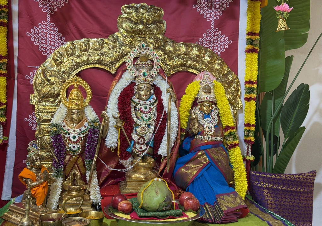 Idols of Lord Rama, Sita, and Lakshmana decorated with flowers and jewelry in a temple setup